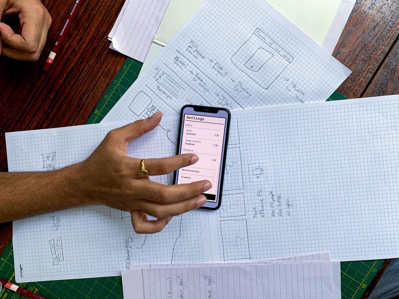 gallery-03 Hand holding smartphone over app design sketches on papers, top view.
